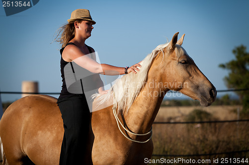 Image of young woman training horse outside in summer