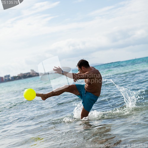 Image of happy young adult man playing beach ball in summer 