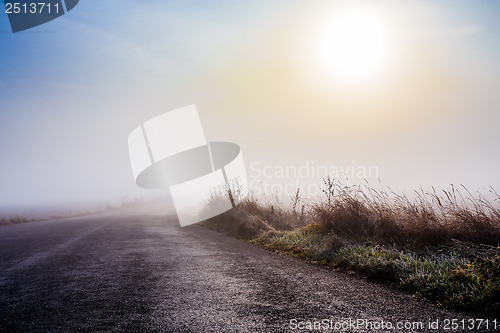 Image of rural foggy road going to the sunrise