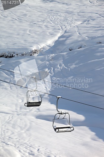 Image of Two chair-lift with snowdrift and off-piste slope in sun morning