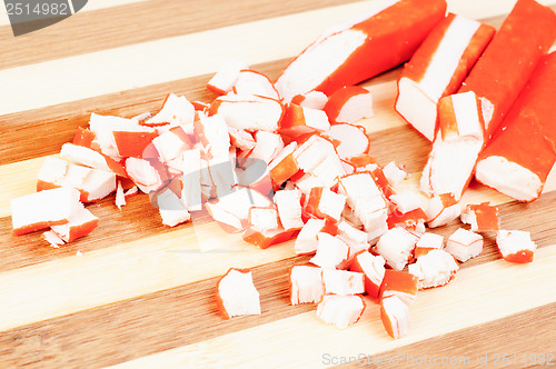 Image of sliced crab sticks on bamboo cutting board