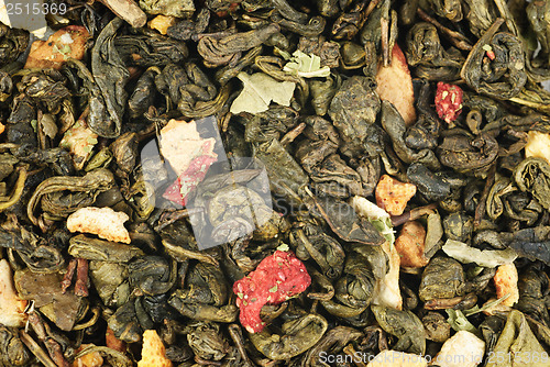 Image of green tea with orange peel and strawberries as background