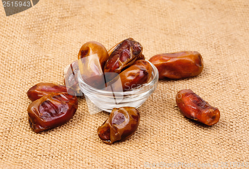 Image of dried dates on glass bowl on canvas background