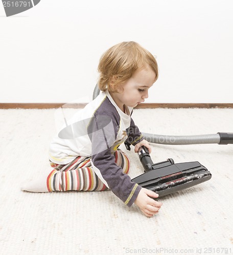 Image of young child cleaning vacuum cleaner