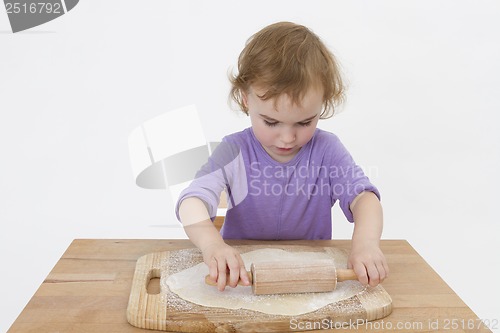 Image of cute curly child rolling out dough