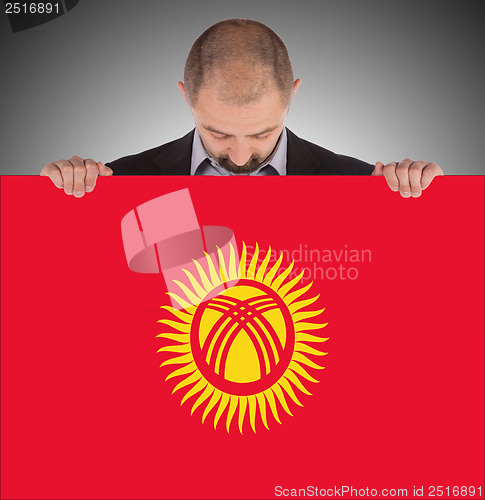Image of Smiling businessman holding a big card or flag