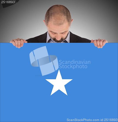 Image of Smiling businessman holding a big card or flag