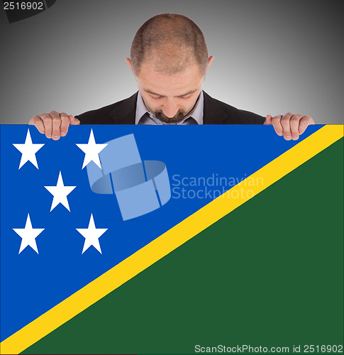 Image of Smiling businessman holding a big card or flag