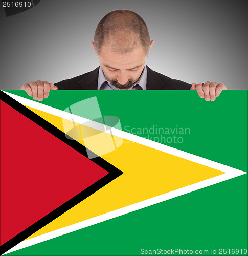 Image of Smiling businessman holding a big card or flag