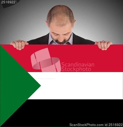 Image of Smiling businessman holding a big card or flag