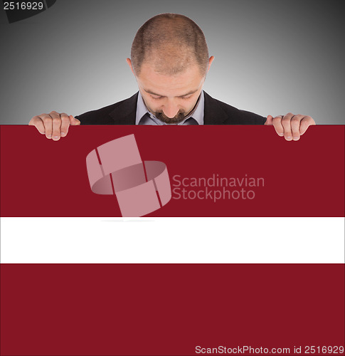 Image of Smiling businessman holding a big card or flag