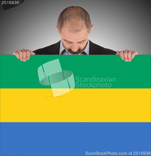 Image of Smiling businessman holding a big card or flag