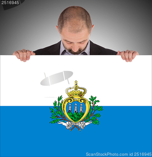 Image of Smiling businessman holding a big card or flag