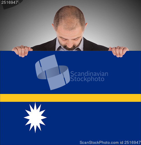 Image of Smiling businessman holding a big card or flag