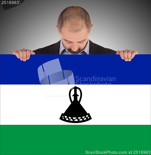 Image of Smiling businessman holding a big card or flag