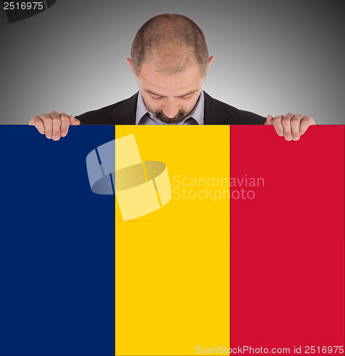 Image of Smiling businessman holding a big card or flag