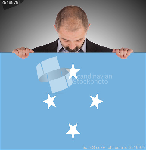 Image of Smiling businessman holding a big card or flag
