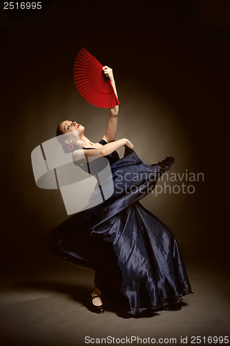 Image of young woman dancing flamenco on black