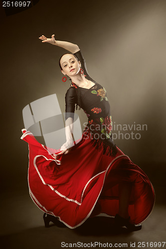 Image of young woman dancing flamenco on black