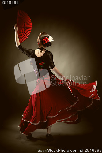 Image of young woman dancing flamenco on black