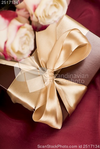 Image of Bouquet of beautiful roses next to a gift