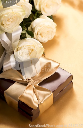 Image of Bouquet of beautiful roses next to a gift