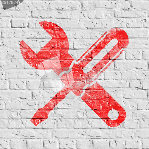 Image of Icon of Crossed Screwdriver on White Brick Wall.