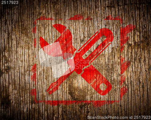 Image of Red Icon of Crossed Screwdriver on Wood.