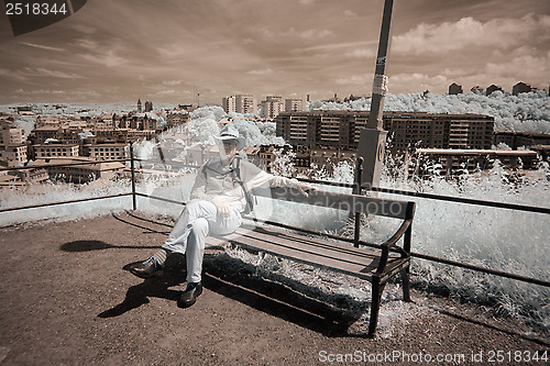 Image of Man on bench with city in background