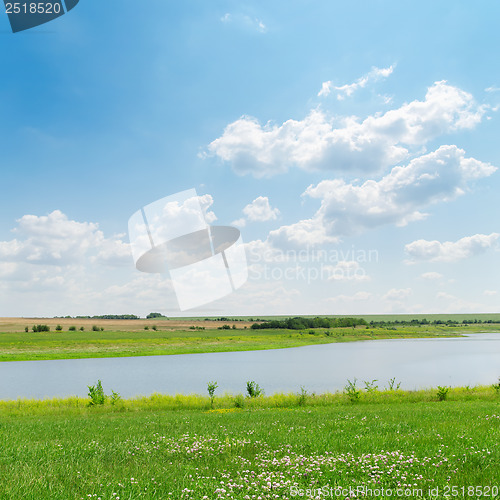 Image of blue sky over river and green grass