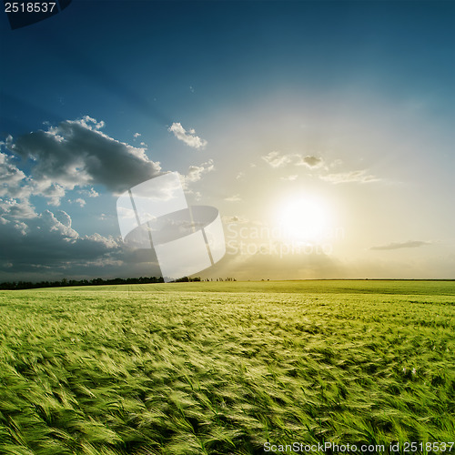 Image of cloudy sunset over green field