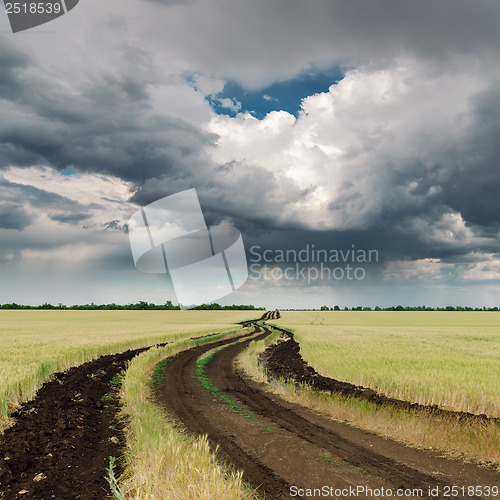 Image of dirty road in field and dramatic sky