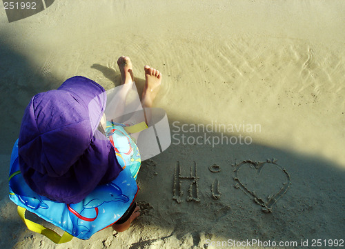 Image of Young child sitting on the sand at the beach