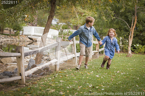 Image of Happy Young Brother and Sister Running Outside