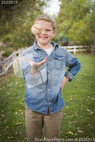 Image of Handsome Young Boy Tossing Up Baseball in the Park