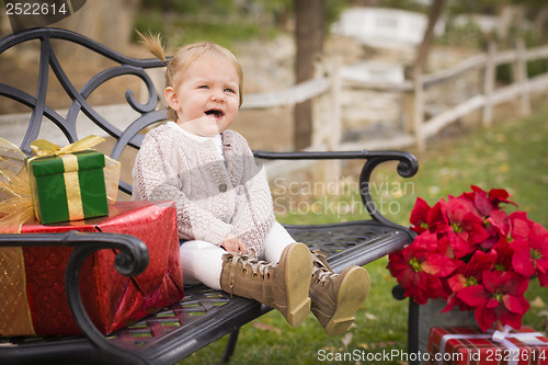Image of Young Toddler Child Sitting on Bench with Christmas Gifts Outsid
