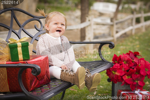 Image of Young Toddler Child Sitting on Bench with Christmas Gifts Outsid