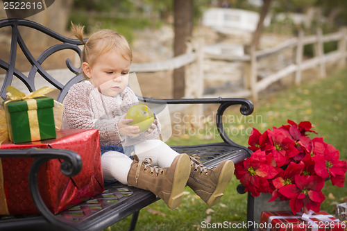 Image of Young Toddler Child Sitting on Bench with Christmas Gifts Outsid