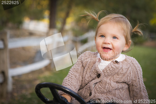 Image of Young Toddler Laughing and Playing on Toy Tractor Outside