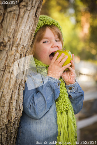 Image of Young Girl Wearing Green Scarf and Hat Eating Apple Outside