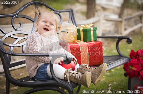 Image of Young Toddler Child Sitting on Bench with Christmas Gifts Outsid