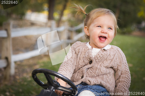 Image of Young Toddler Laughing and Playing on Toy Tractor Outside