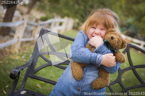 Image of Cute Smiling Young Girl Hugging Her Teddy Bear Outside