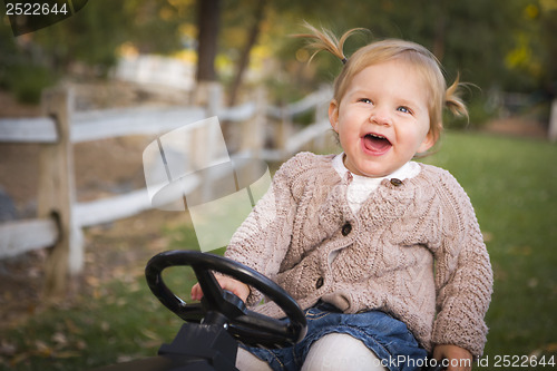 Image of Young Toddler Laughing and Playing on Toy Tractor Outside