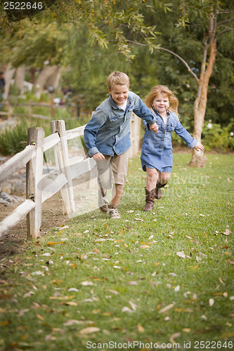 Image of Happy Young Brother and Sister Running Outside