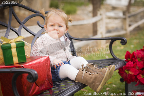 Image of Young Toddler Child Sitting on Bench with Christmas Gifts Outsid