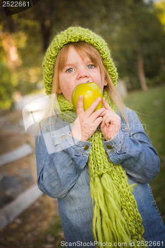 Image of Young Girl Wearing Green Scarf and Hat Eating Apple Outside
