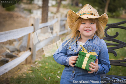 Image of Young Girl Wearing Holiday Clothing Holding Christmas Gift Outsi