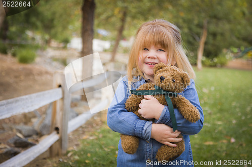 Image of Cute Smiling Young Girl Hugging Her Teddy Bear Outside
