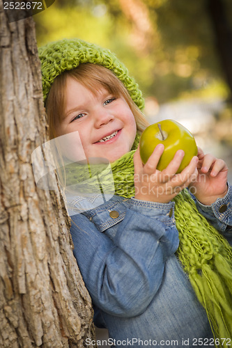 Image of Young Girl Wearing Green Scarf and Hat Eating Apple Outside